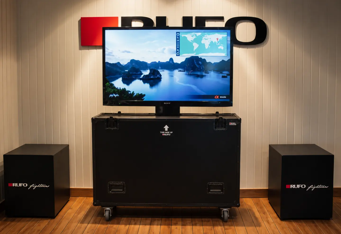 RUFO TV-flightcase med skjerm på toppen, vist i showroom med RUFO-logo på veggen