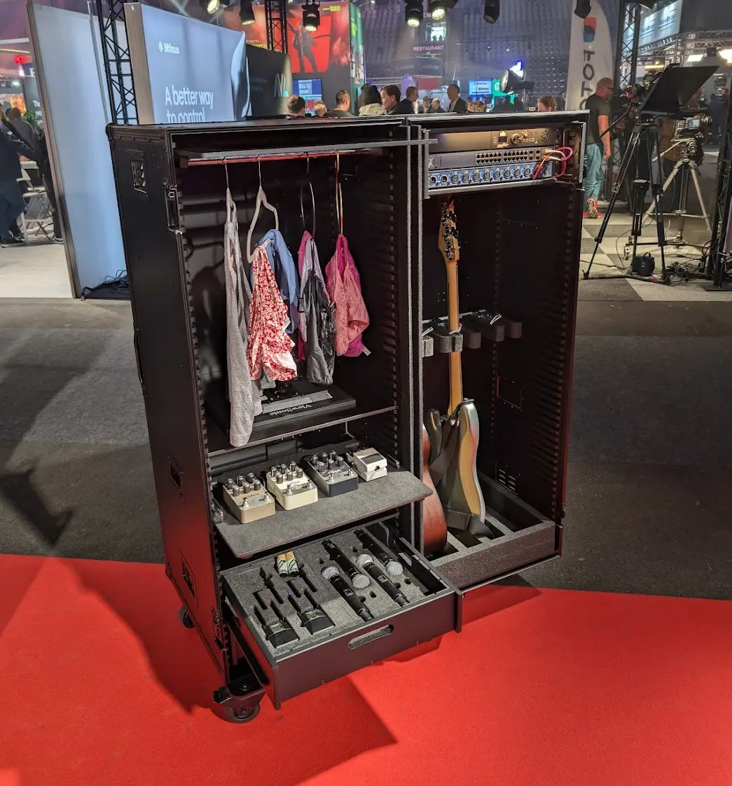 Åpen Rufo flightcase for backline med gitar, pedalbrett, mikrofoner og klær på messe